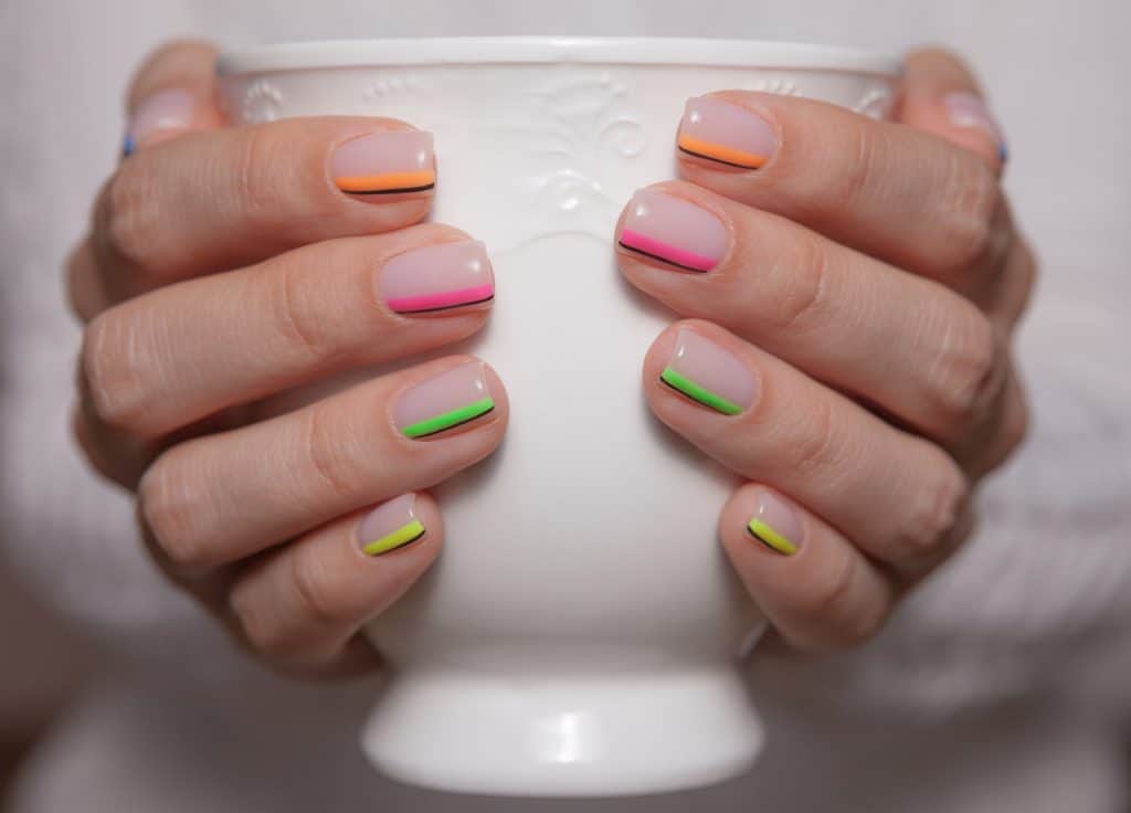 Close-up. Women's hands with a beautiful color manicure and white ceramic cup