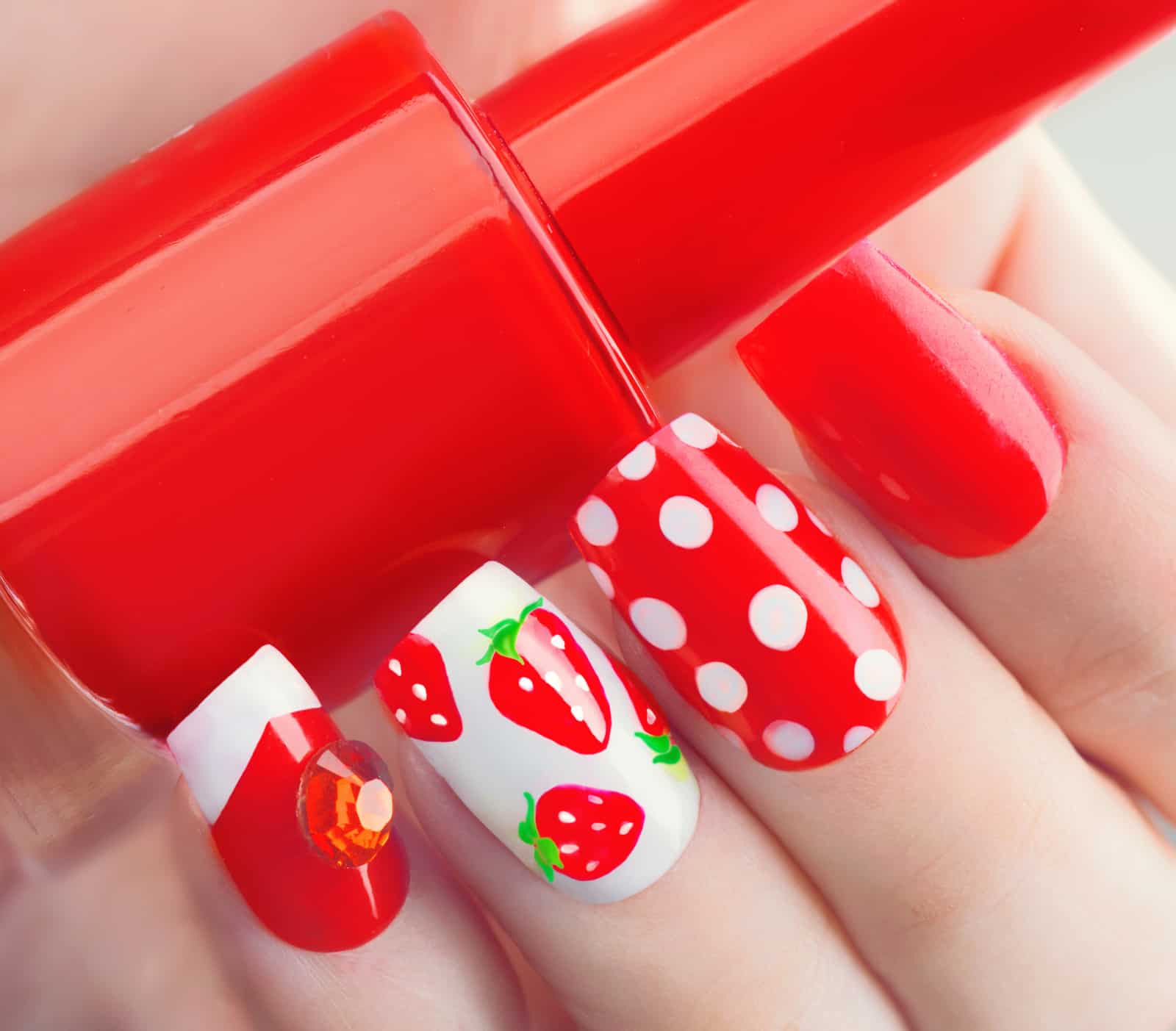 Nail art manicure. Summer style red manicure with strawberries and polka dots