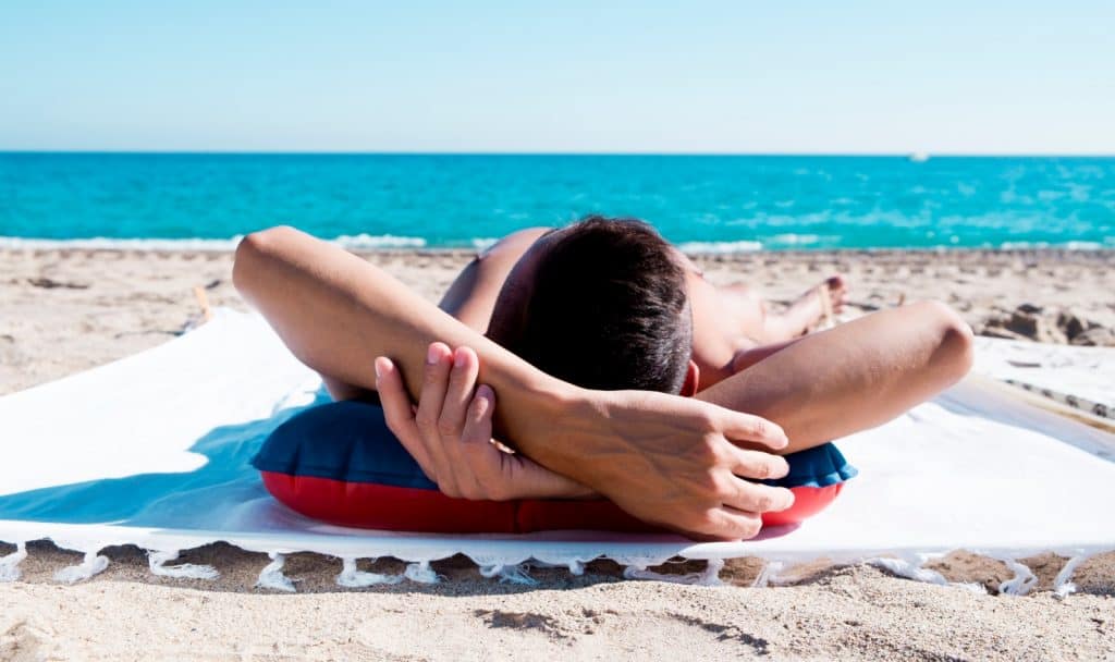 a man tanning in front of the beautiful beach