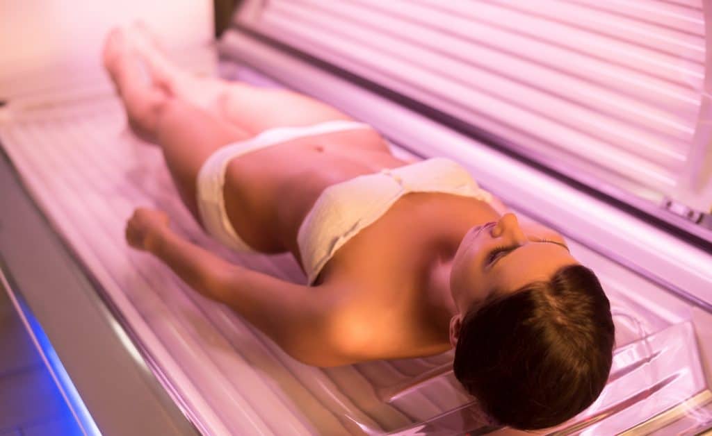 woman wearing a white bikini on a tanning bed