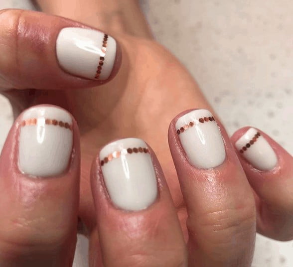 white indie nail design with gold dots lined below the tip of the nails