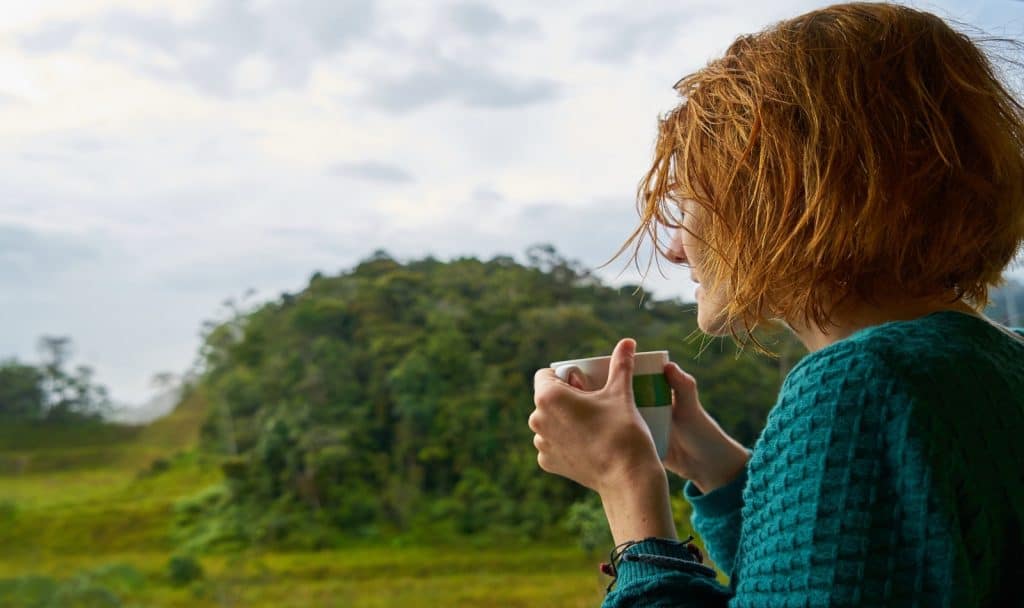 a lady with short hair drinking coffee in front of their house