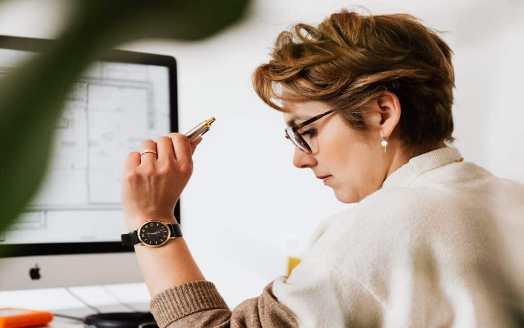 short hair working woman holding her pen in front of her computer