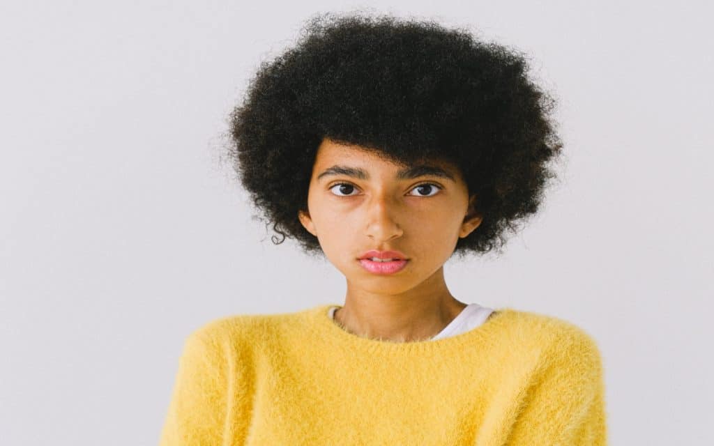 a girl in yellow sweater with very thick short hair