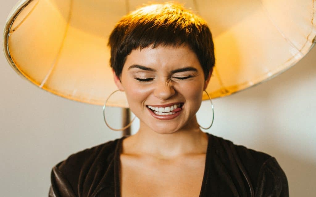 a cute short hair lady in front of a yellow lamp