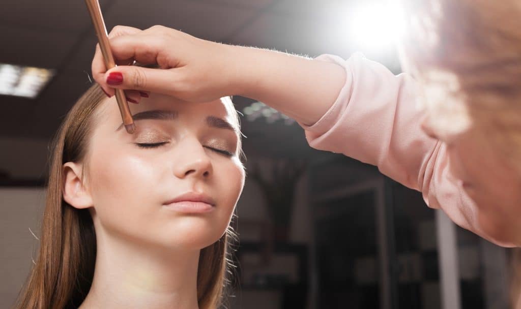 Makeup artist applying an eyeshadow primer on an eyelid of a woman