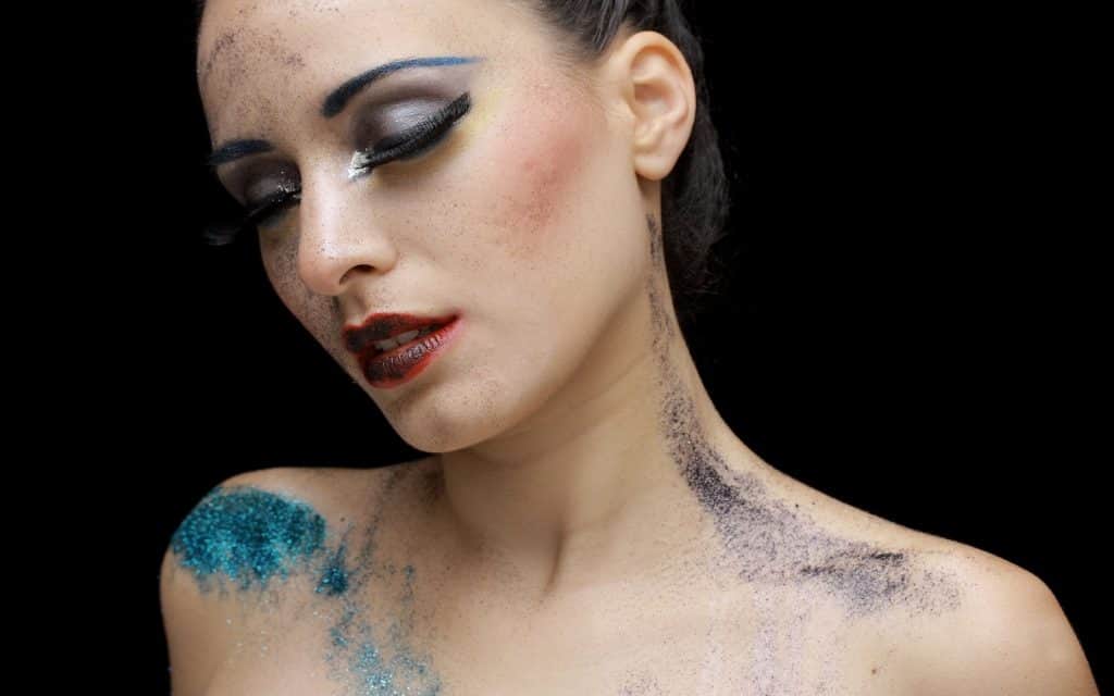 a lady with make up and paint on her face and body posing for a great makeup picture