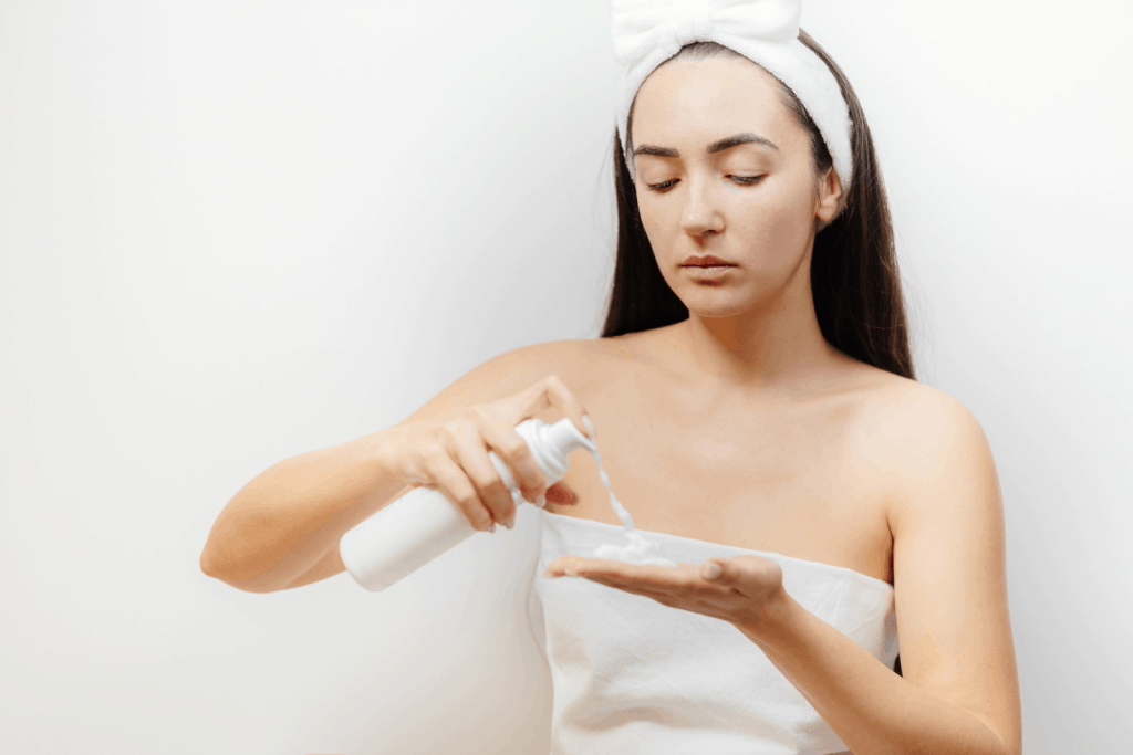 a lady in white putting facial foam cleanser on her hands to use for double cleansing