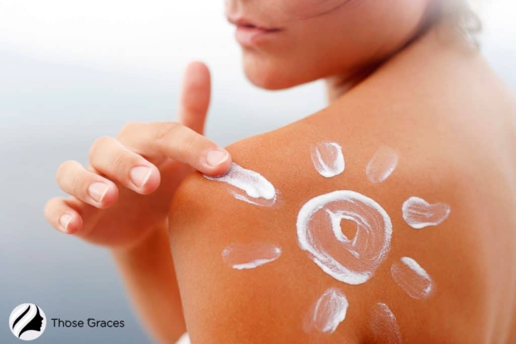 a woman putting sunscreen in a shape of a sun on her back