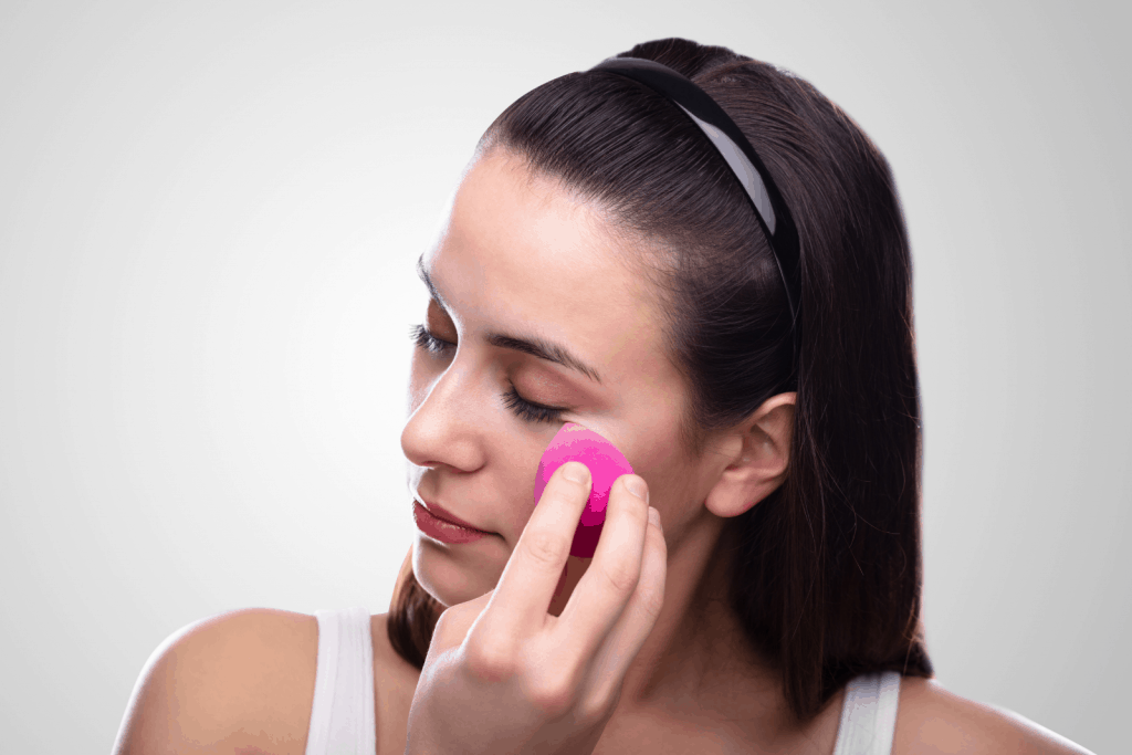 a lady demonstrating  how to use Real Techniques sponge pink miracle sponge