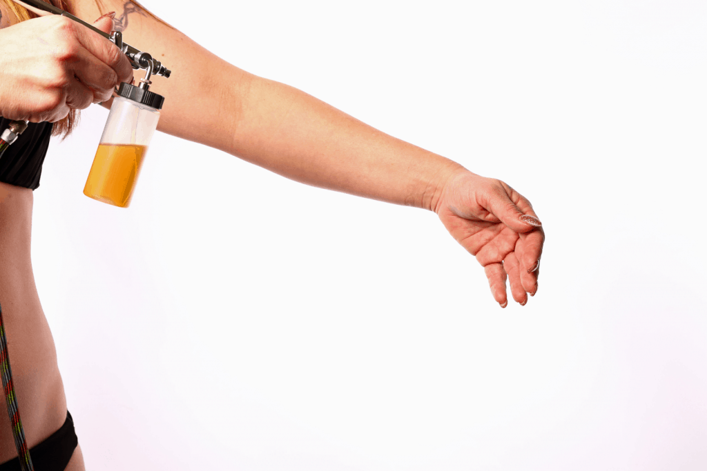 using a spray tan machine, a lady is getting a DIY tanning at home