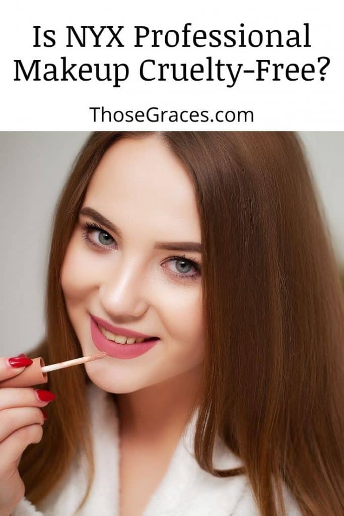 a pretty lady with blue eyes facing in front of the camera while putting a nude pink lipstick
