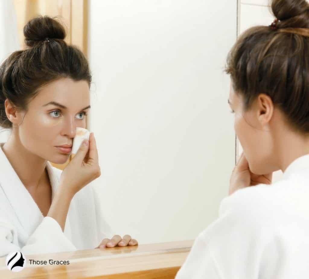 a girl removing her makeup in front of a wide mirror