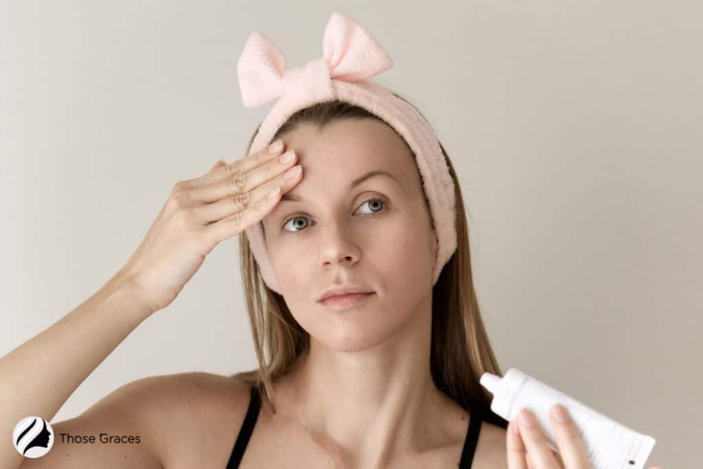 lady with hairband putting cream on her forehead