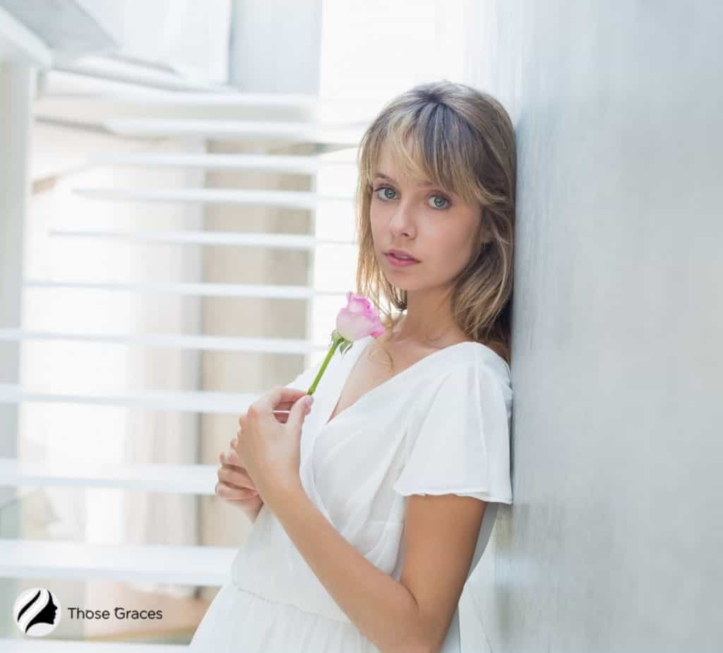 woman with side bangs holding a rose