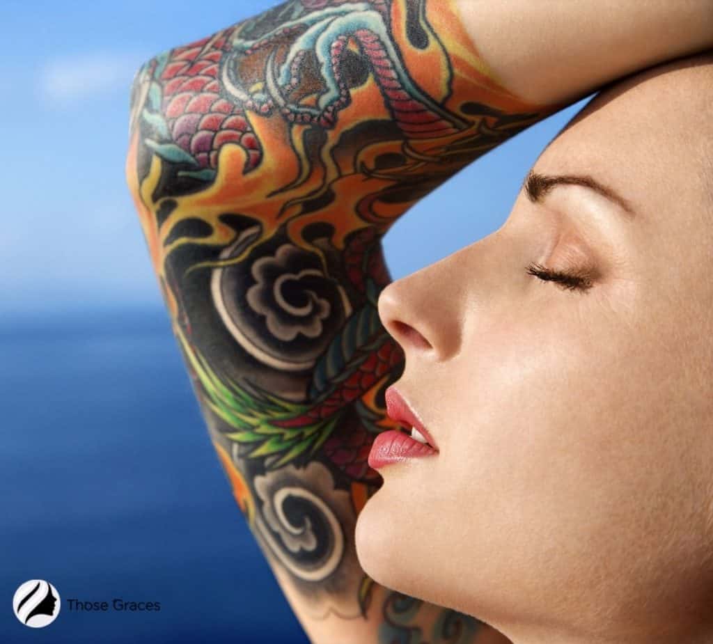 close-up shot of a lady's face and shoulder with colorful tattoos