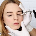 an expert putting a permanent makeup eyeliner to the lady's eyes