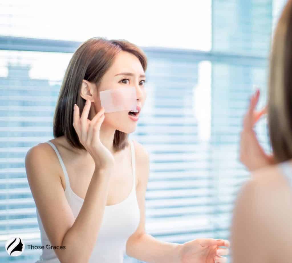 lady with blotting paper on her oily face