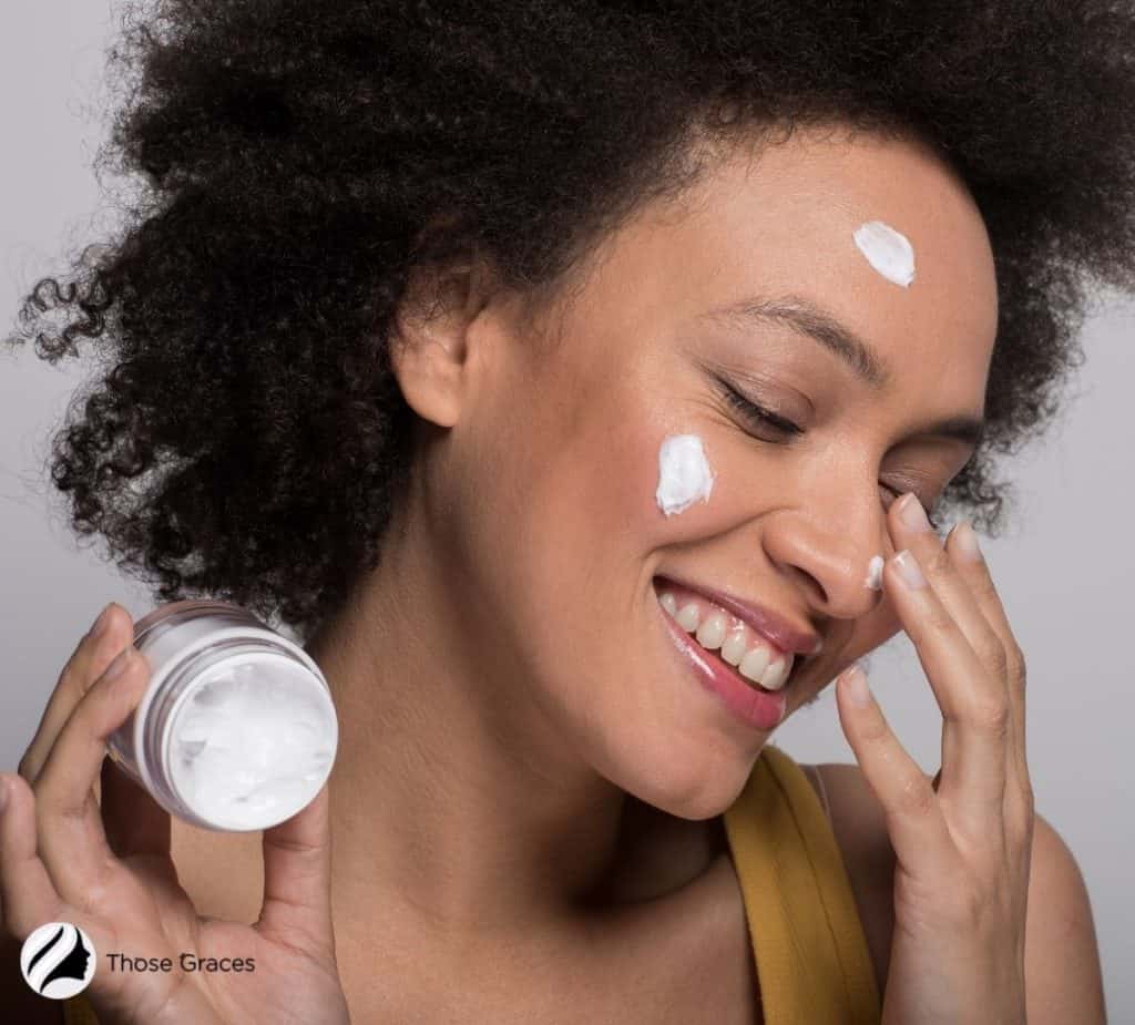 pretty curly-haired lady putting moisturizing cream on her face