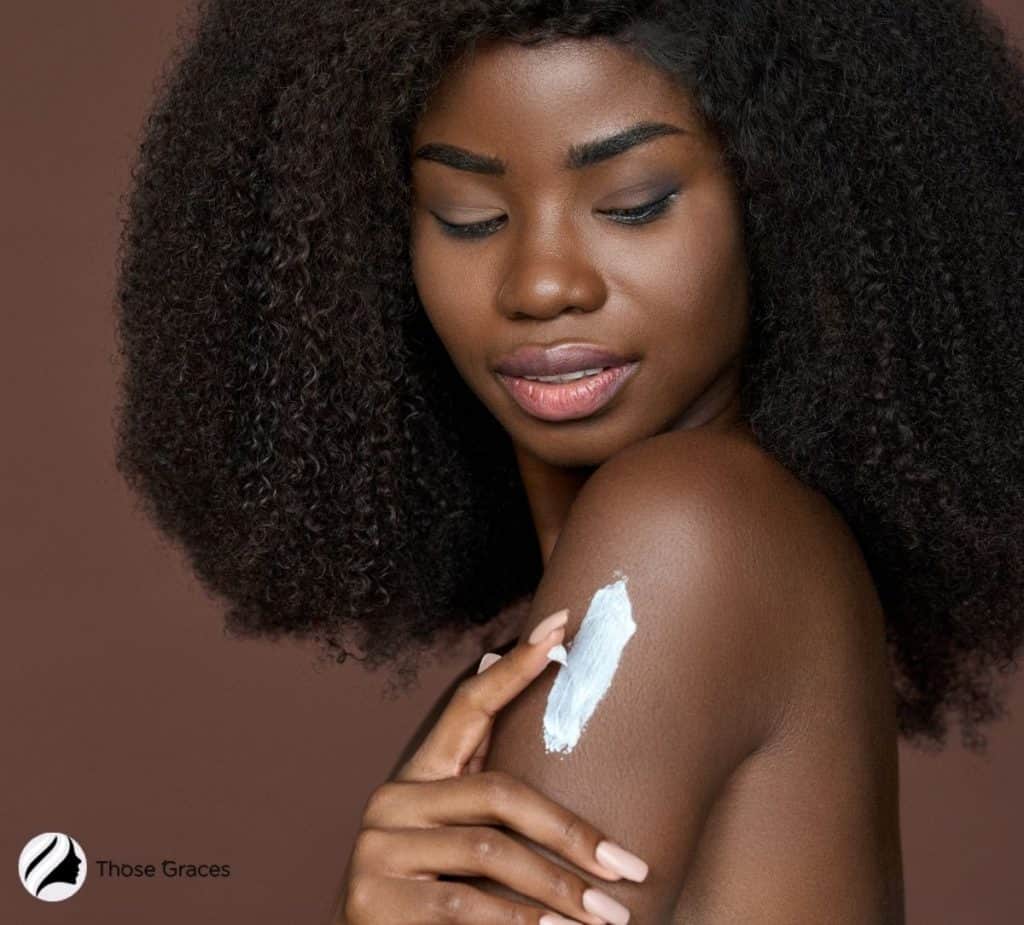 black woman putting sunscreen on her arms