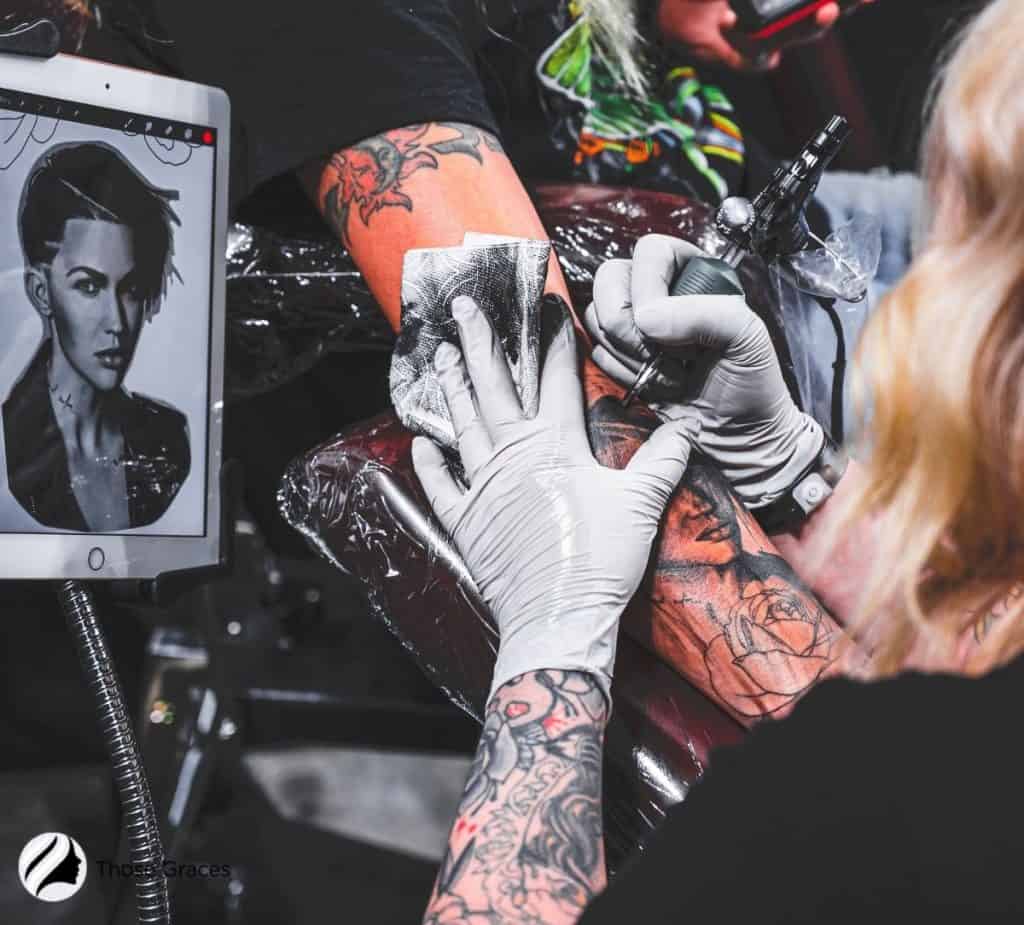 lady tattooing the man's arms