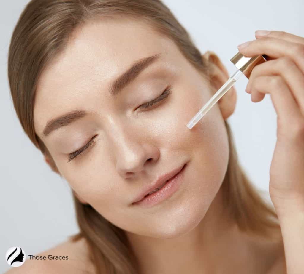 Lady applying serum on face.