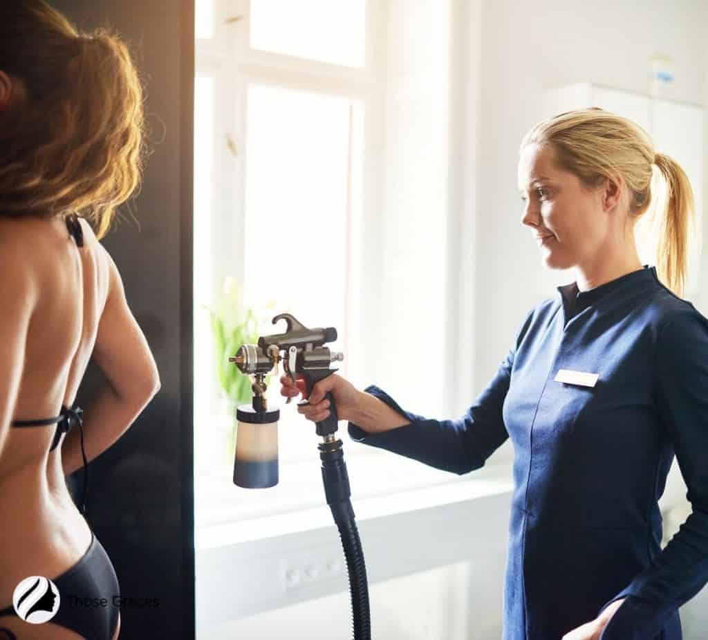 a woman being spray tanned by another woman