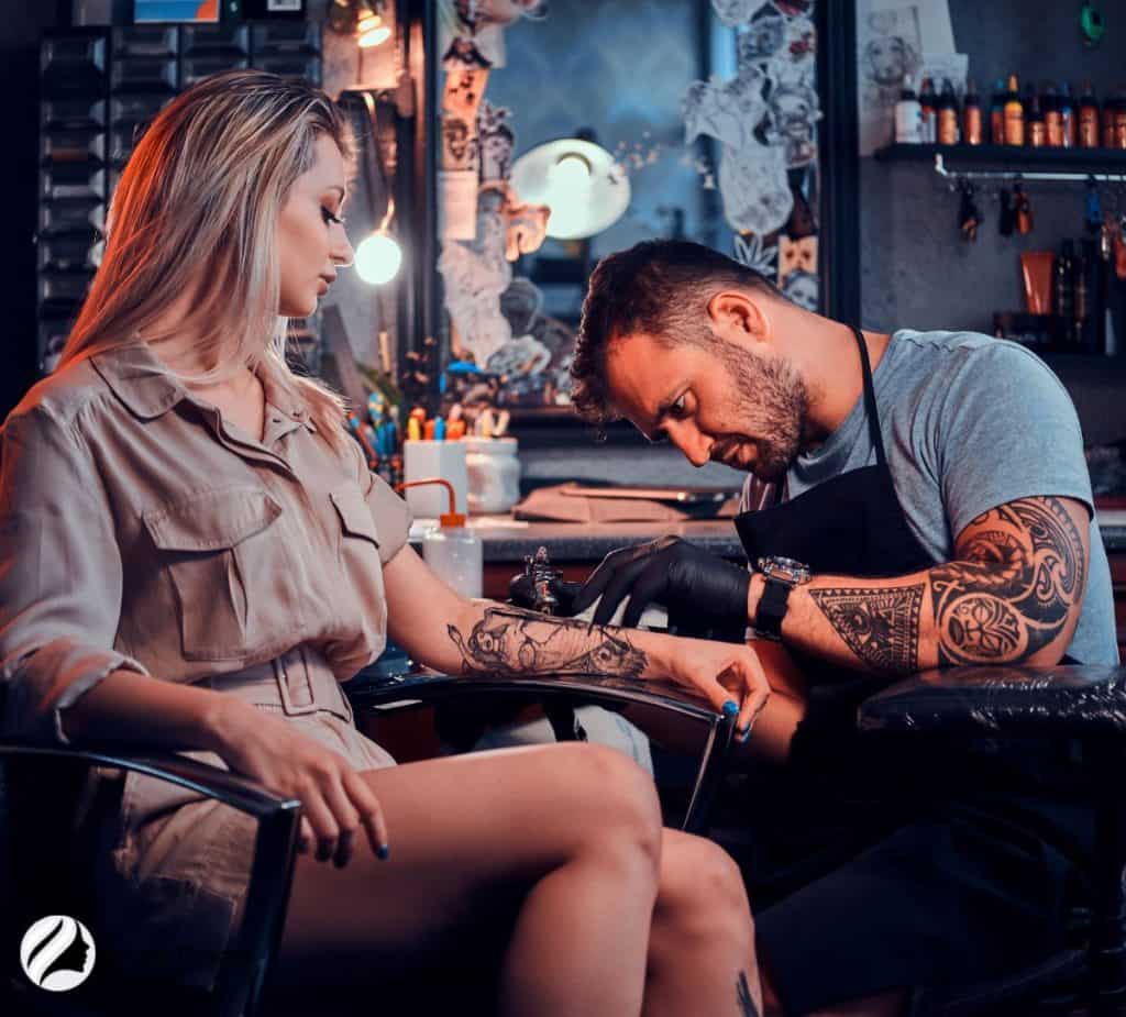 women getting tattoo from an artist 