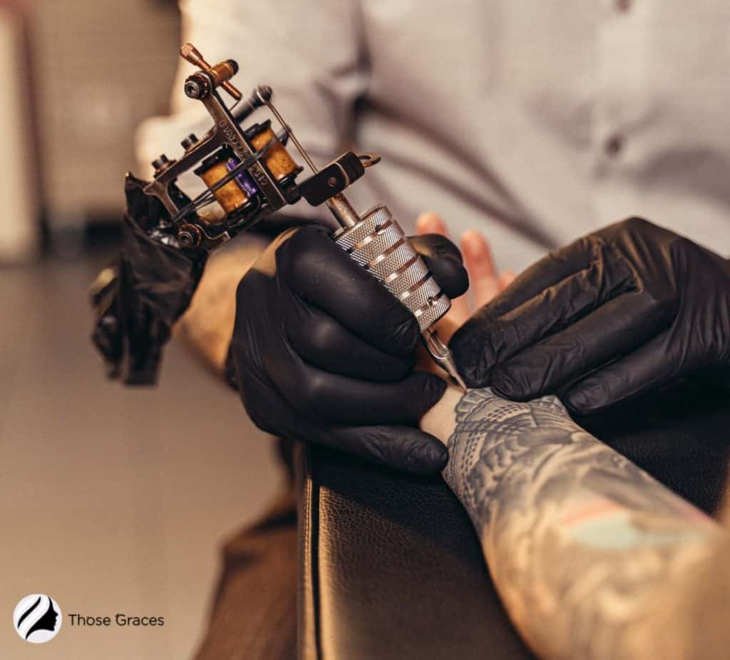 men doing machine tattooing on hand