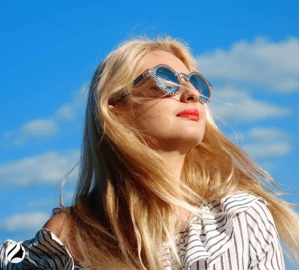 blonde lady looking up the sun