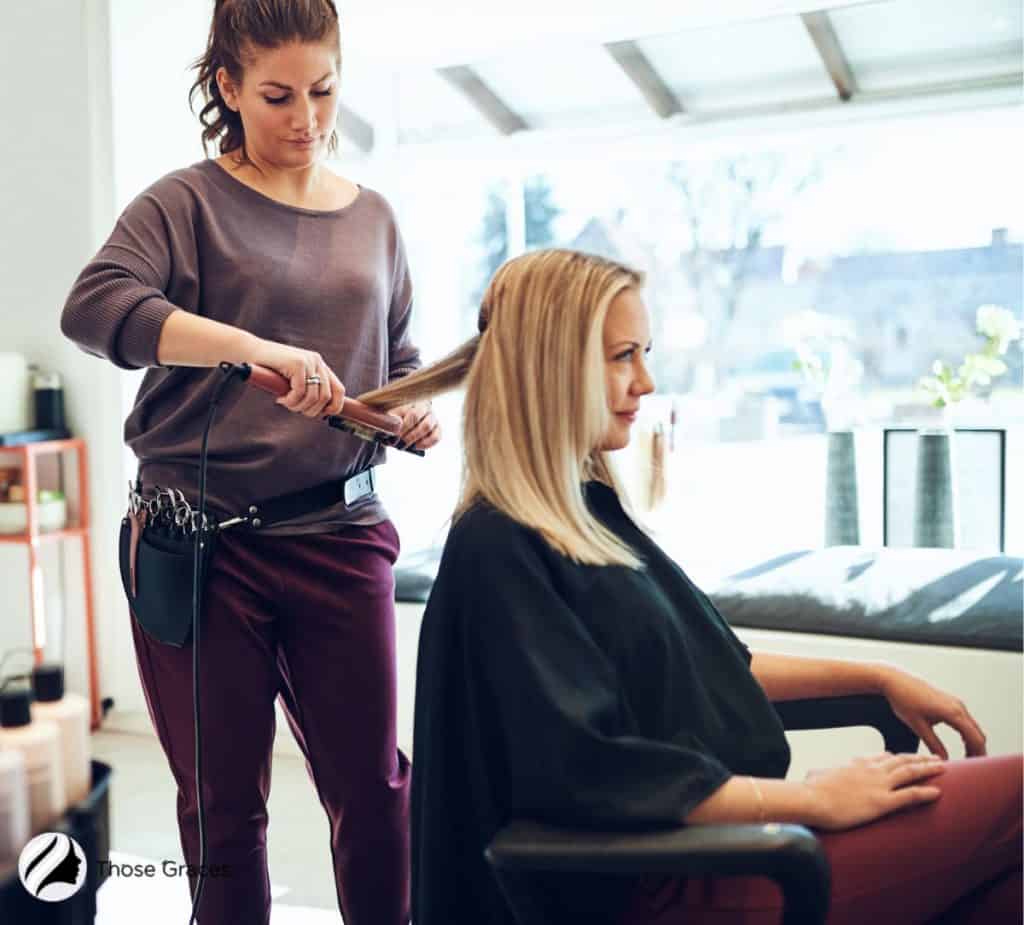 hair professional straightening the hair of the blonde woman