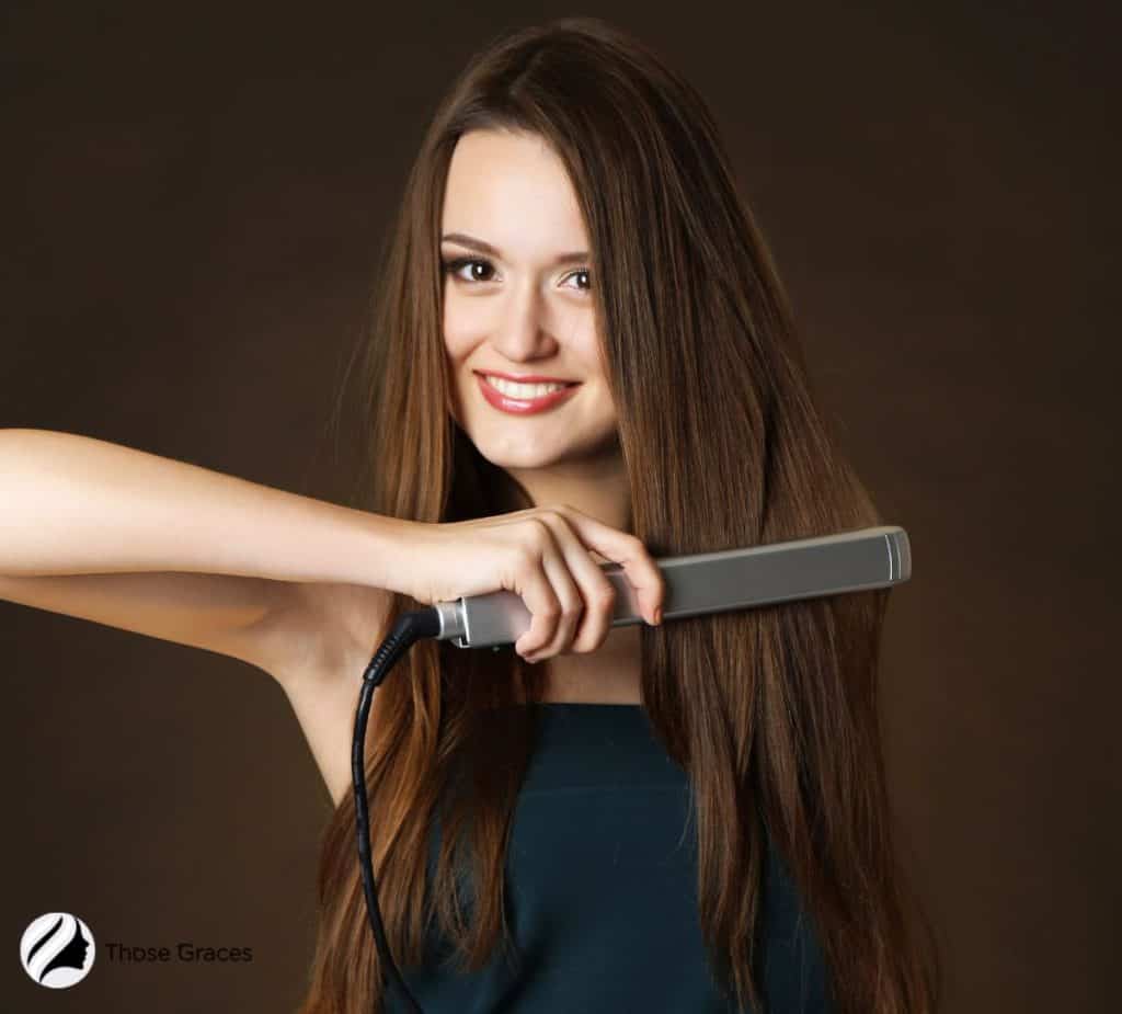 woman using a flat iron to straight her hair