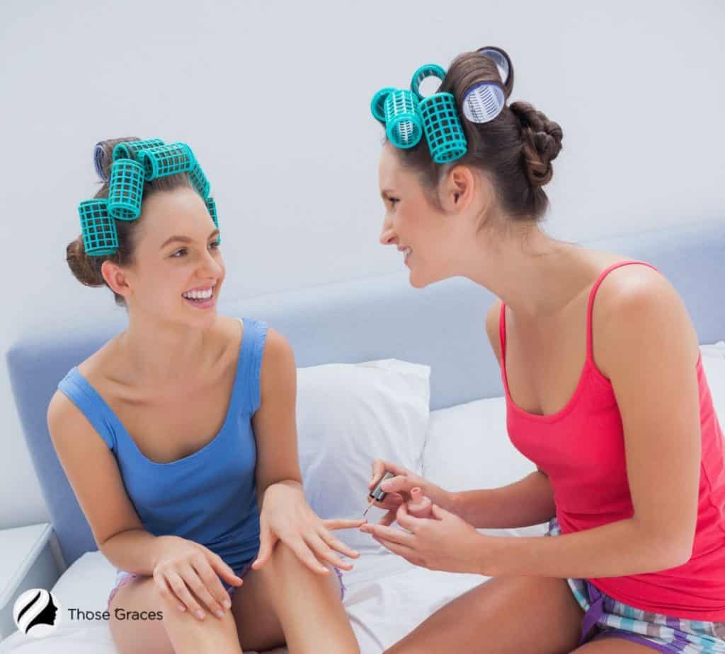 2 woman with roller on their hair and doing manicures