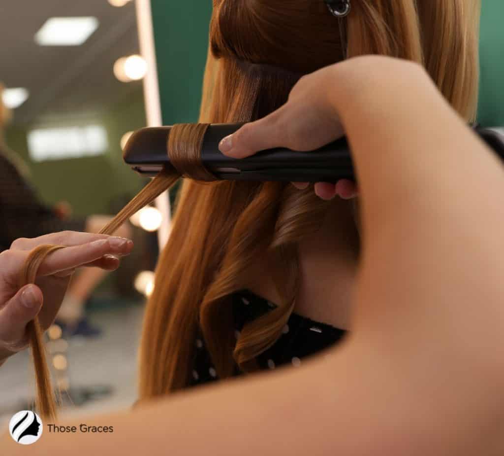 woman curling her hair using a flat iron