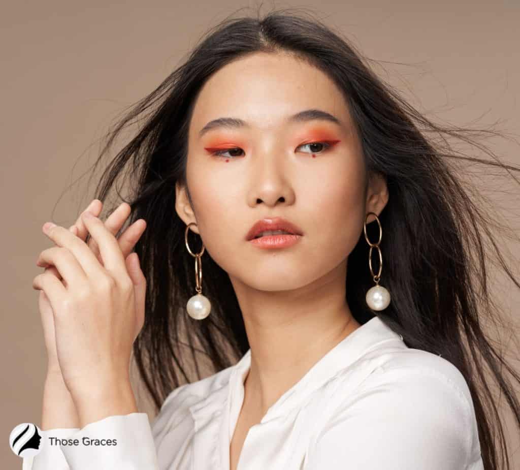 Asian model wearing gold earrings with pearl